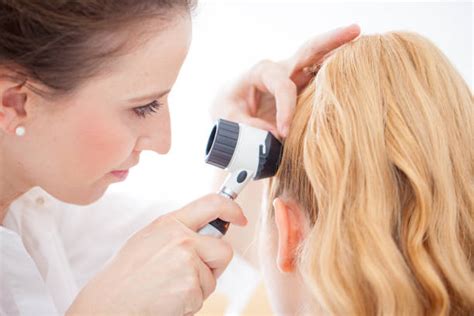 Medico che esamina il cuoio capelluto di un paziente con una lente d'ingrandimento