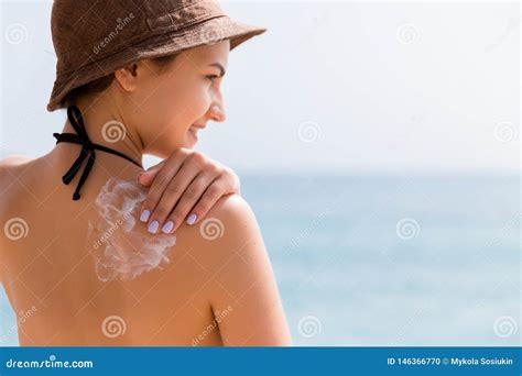 Bambino che gioca in spiaggia con cappello e crema solare