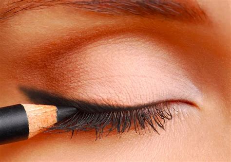 Ragazza che applica matita occhi nera