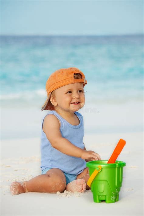 Bambino che gioca sulla spiaggia con la sabbia, con la crema solare visibile