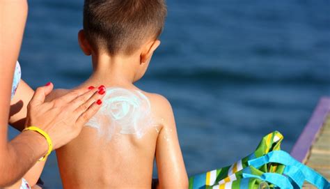 Persona con tatuaggio che si protegge dal sole con crema solare