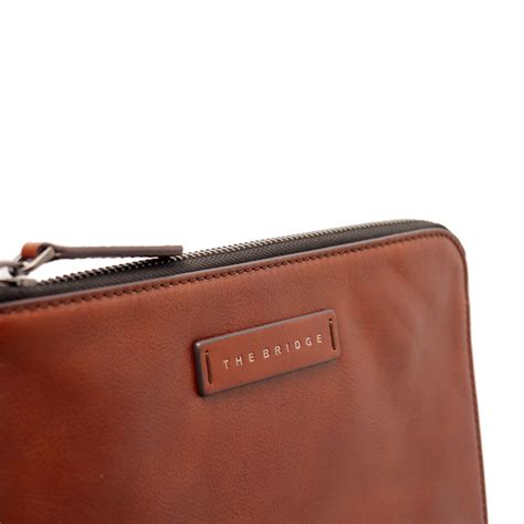 Dettaglio di una pochette in pelle marrone firmata The Bridge, con logo inciso