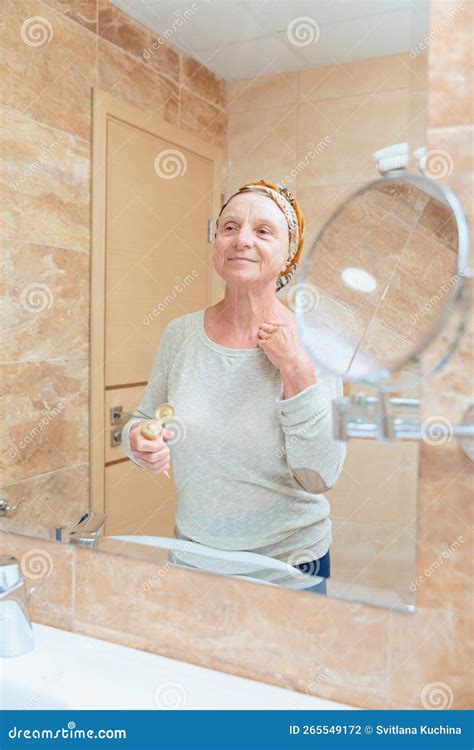 Donna matura che applica crema viso