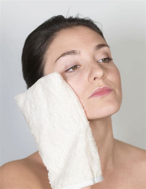 Persona che utilizza un guanto struccante sul viso