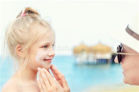 Bambino che applica la protezione solare con l'aiuto di un genitore