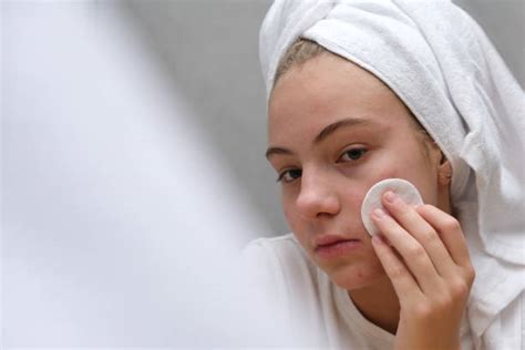 Donna che si strucca il viso con un batuffolo di cotone