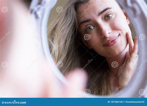 Ragazza che si guarda allo specchio con preoccupazione per i brufoli