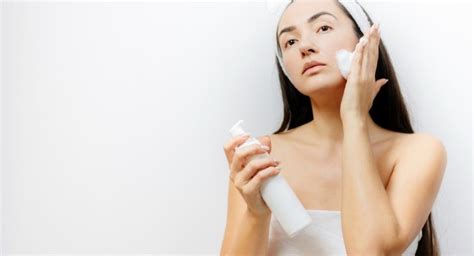 Donna che applica latte detergente sul viso