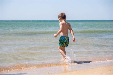 Bambino felice che gioca in spiaggia con crema solare
